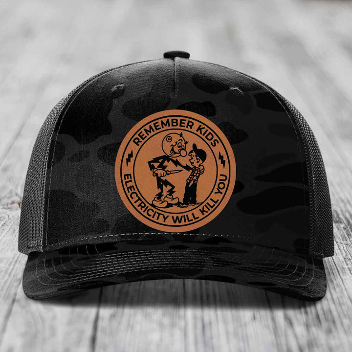Black camouflage trucker hat with a brown circular leather patch reading &