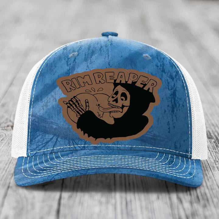 Blue and white trucker hat with a brown leatherette patch featuring a skeleton holding a basketball and the text &