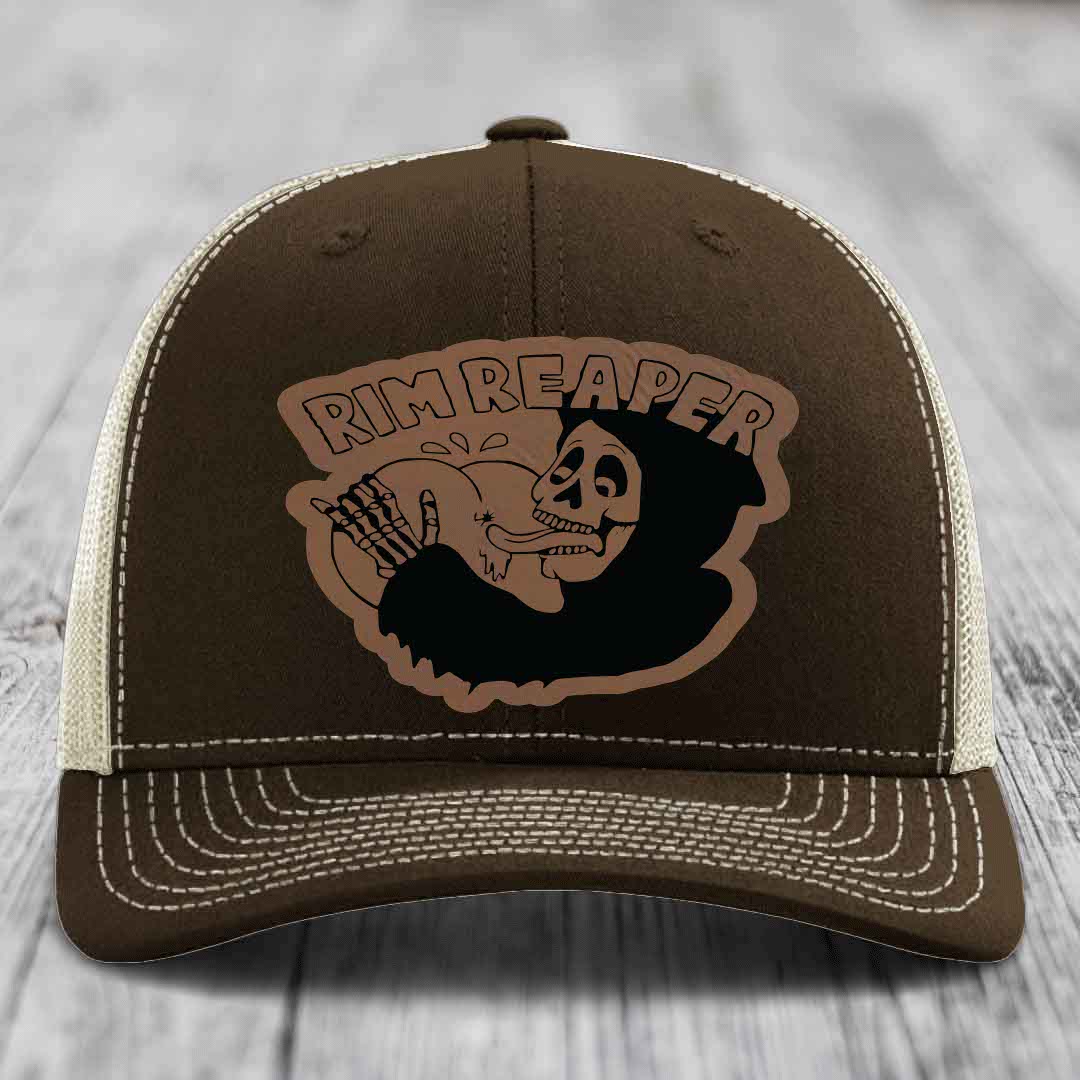 Brown trucker hat with white stitching and a skull graphic patch that says &