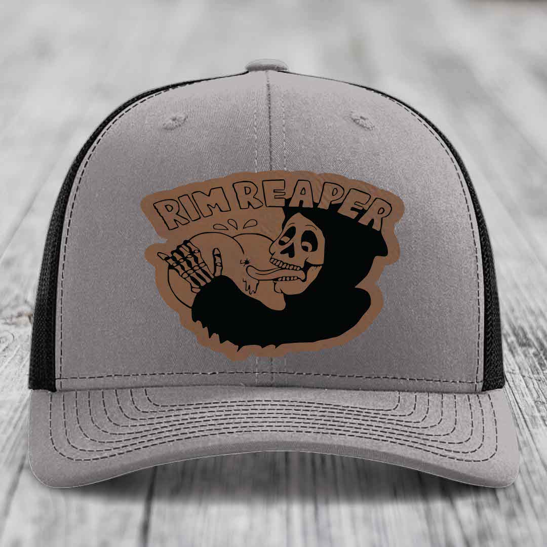 Grey trucker hat with black mesh back and brown leather patch featuring a skeleton holding a basketball and text &
