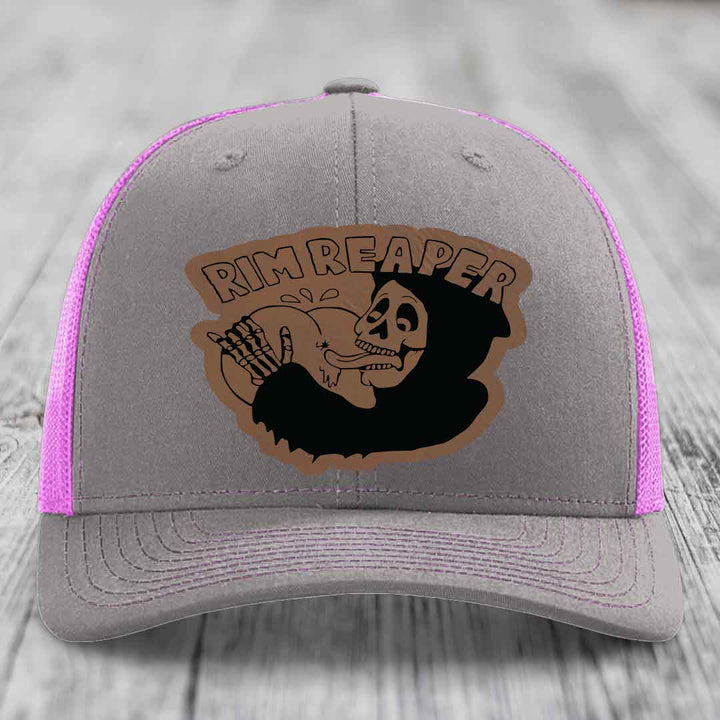 Grey trucker hat with pink mesh sides and a brown leather patch featuring a skeleton holding a basketball and the text &