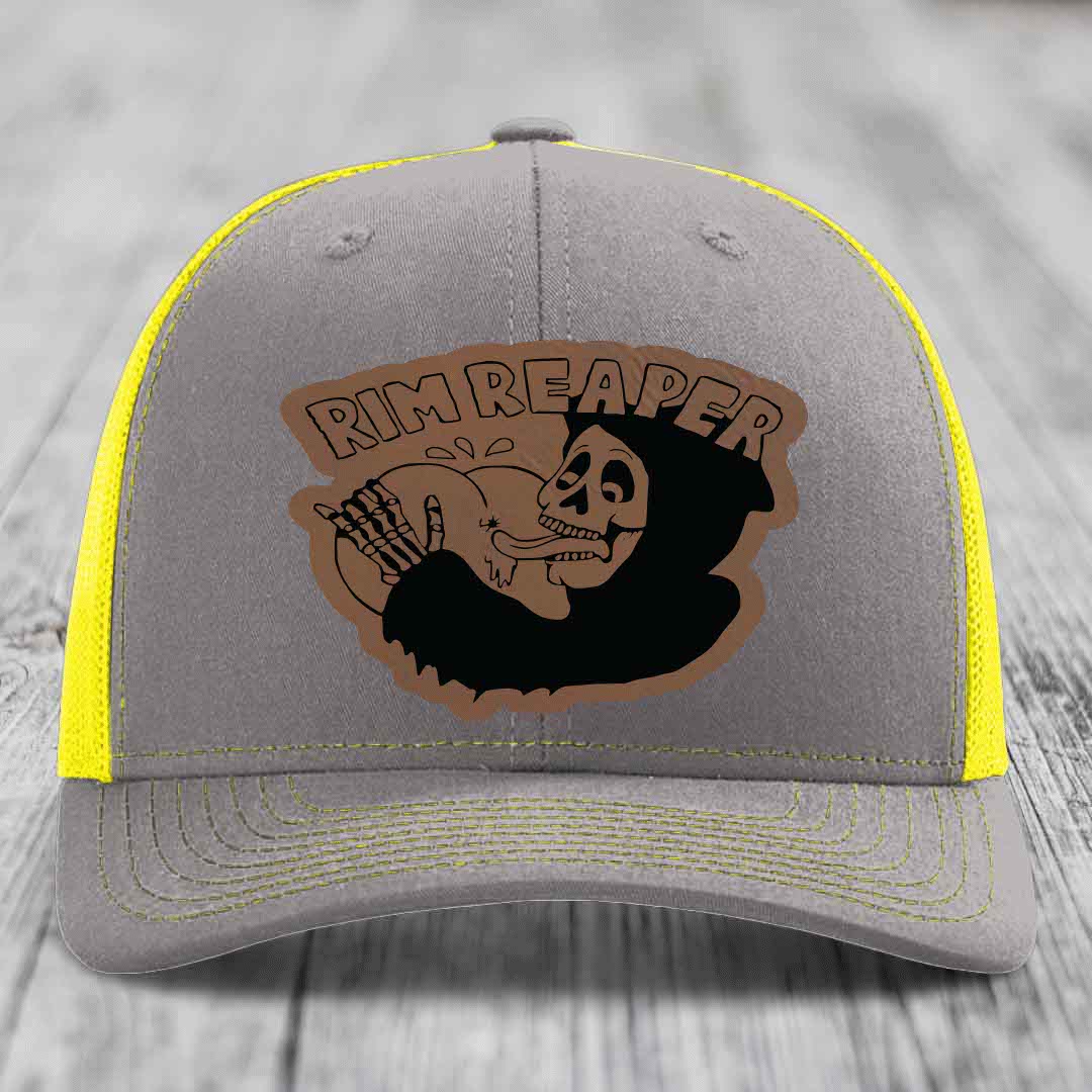 Grey trucker hat with yellow mesh and stitching, featuring a brown leatherette patch of a skeleton holding a basketball with &