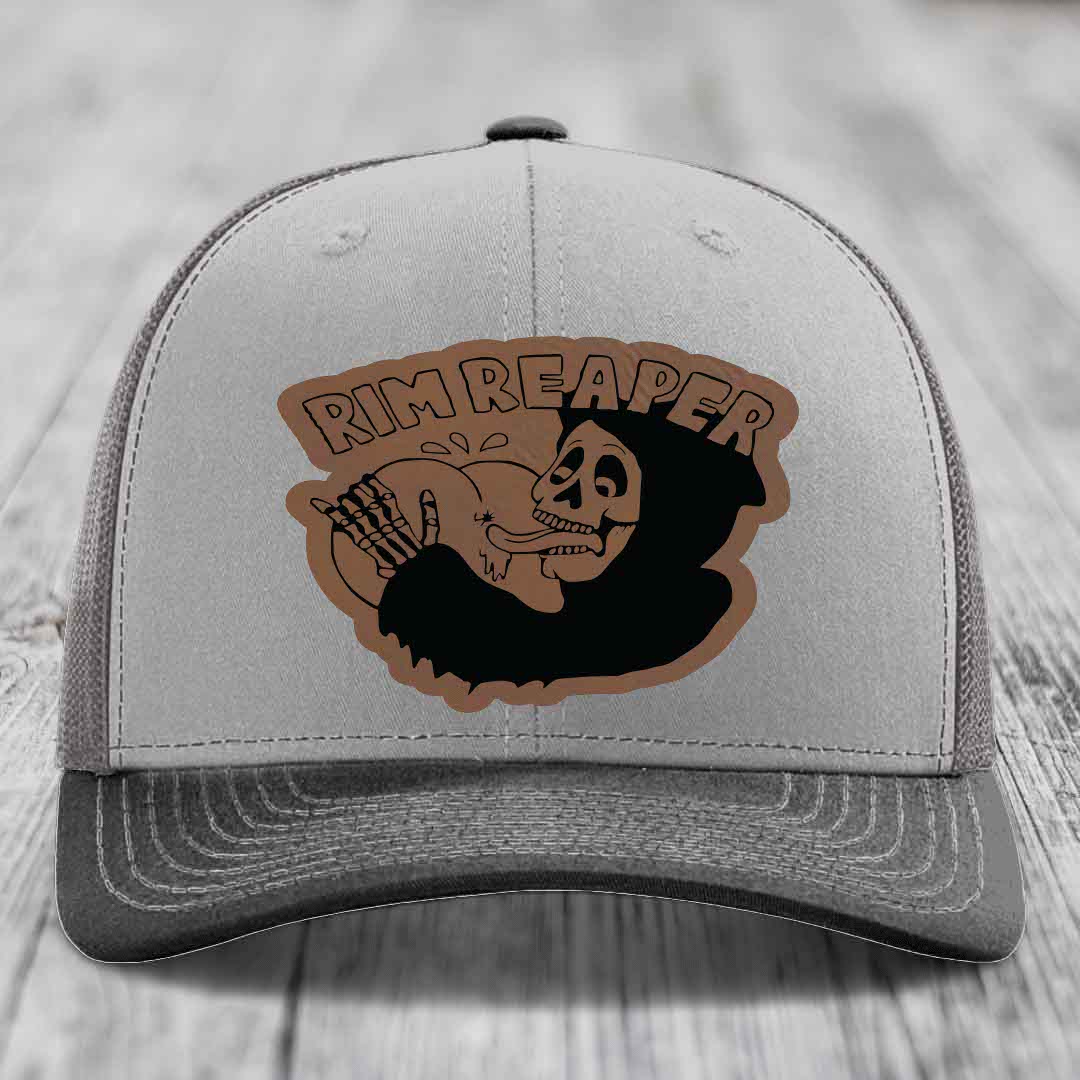 Grey trucker hat with brown leather patch featuring skull and &