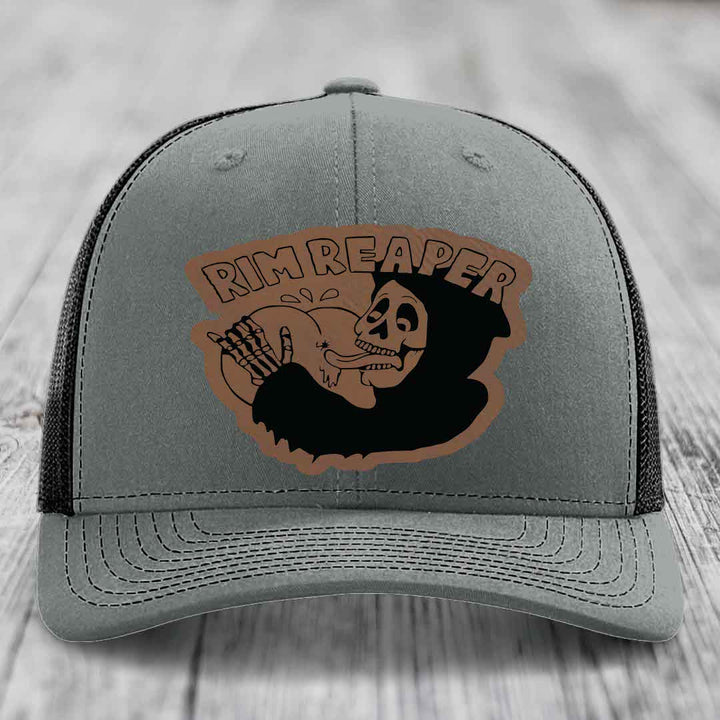 Grey trucker hat with black mesh back and brown leather patch featuring a skeleton holding a basketball and the text &