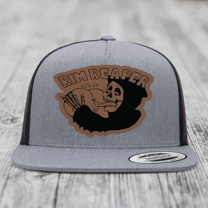 Grey trucker hat with brown leather patch featuring skull holding basketball and &