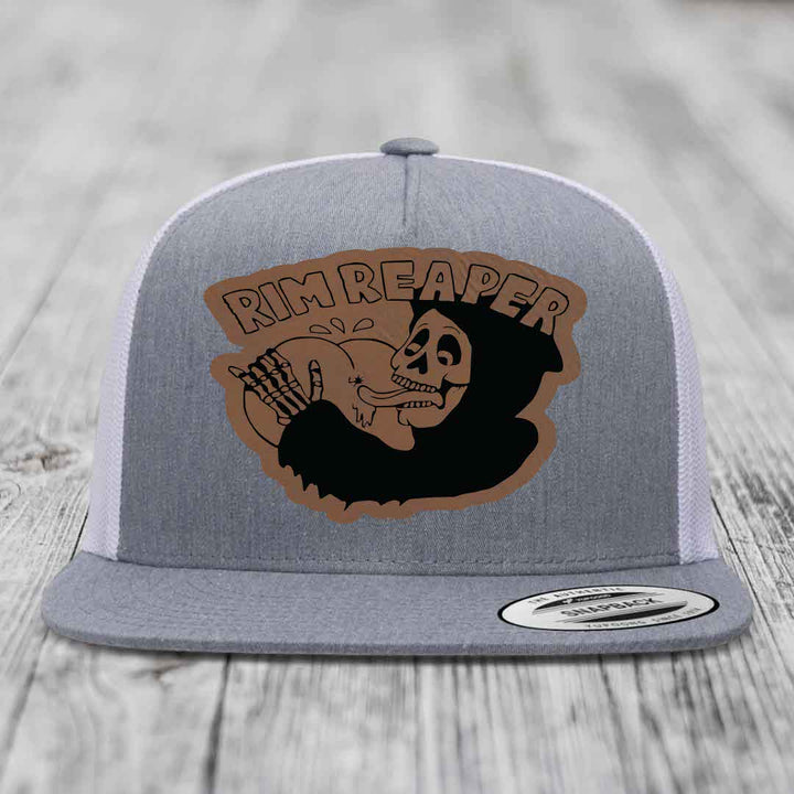 Grey trucker hat with brown leatherette patch featuring skull holding basketball and &