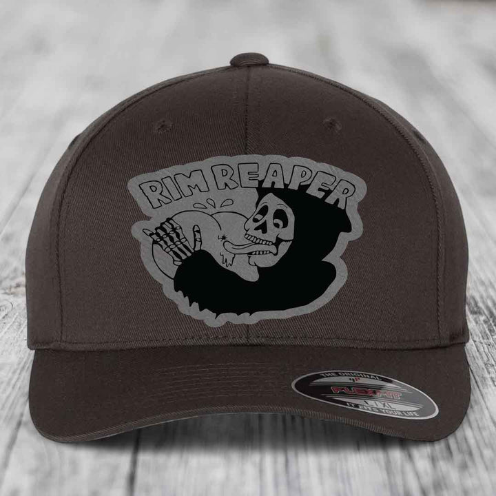 Dark brown Flexfit hat with a grey and black Rim Reaper skull patch on front.