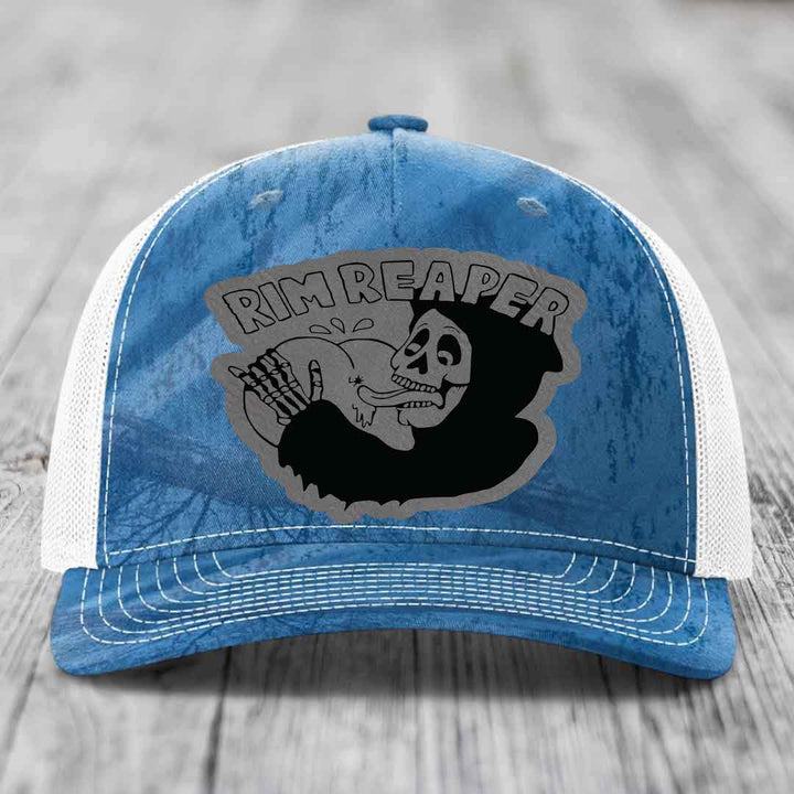 Blue and white trucker hat with a black skull graphic and &