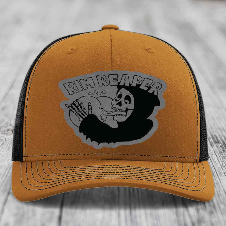 Tan trucker hat with black mesh back and gray skull patch that says Rim Reaper