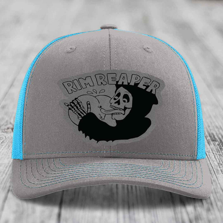 Grey trucker hat with blue mesh sides and a black Rim Reaper skull patch on front.