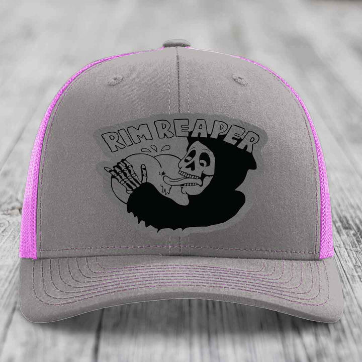 Grey trucker hat with pink mesh sides and a black &