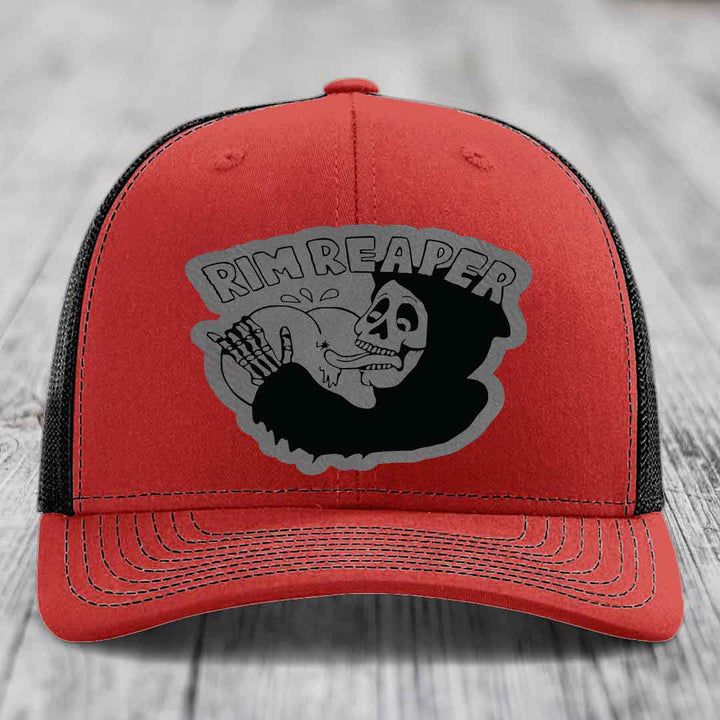 Red trucker hat with black mesh back and gray skull graphic that says Rim Reaper