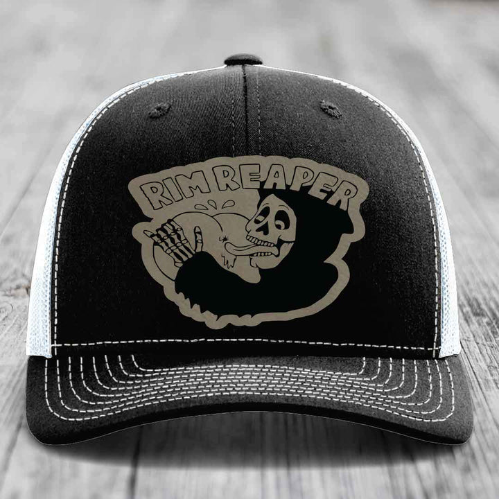 Black trucker hat with white stitching and a grey &