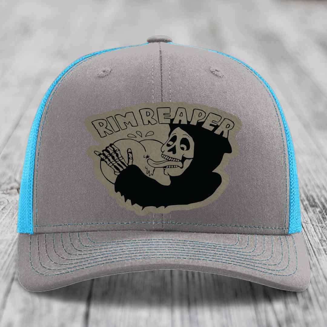 Grey trucker hat with blue mesh sides and a black skull graphic patch that says Rim Reaper.