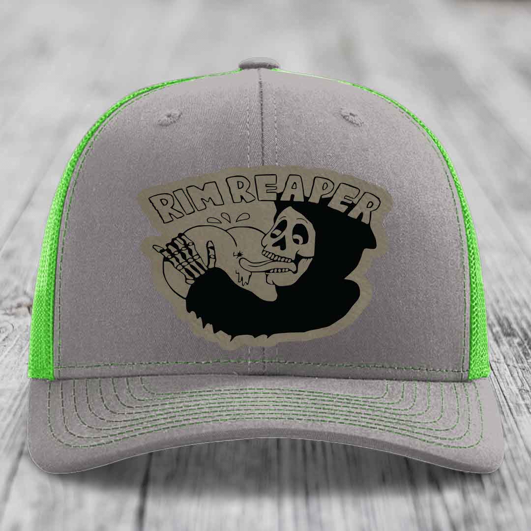 Grey trucker hat with neon green mesh and stitching, featuring a black skull graphic and &
