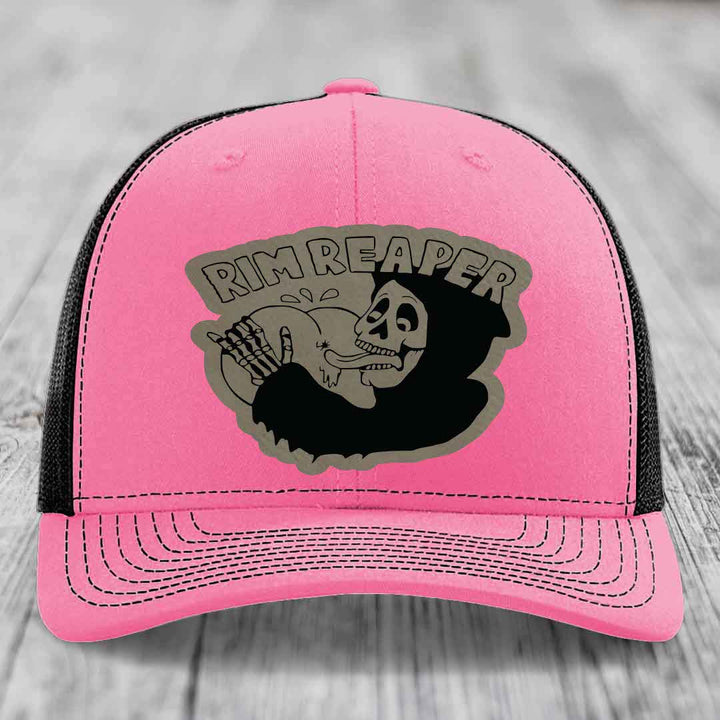 Pink trucker hat with black mesh back and gray skull patch that says &