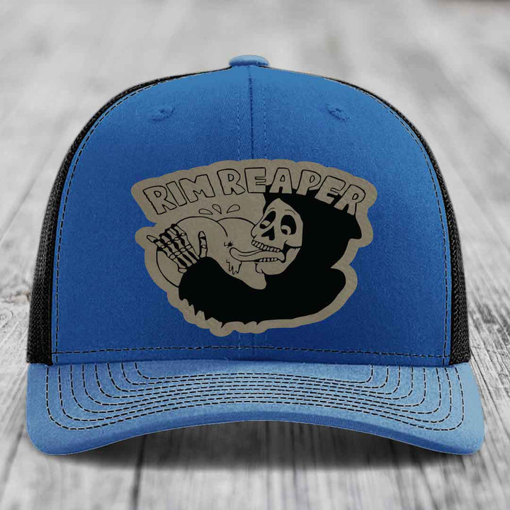 Blue trucker hat with black mesh back and gray skull patch that says &