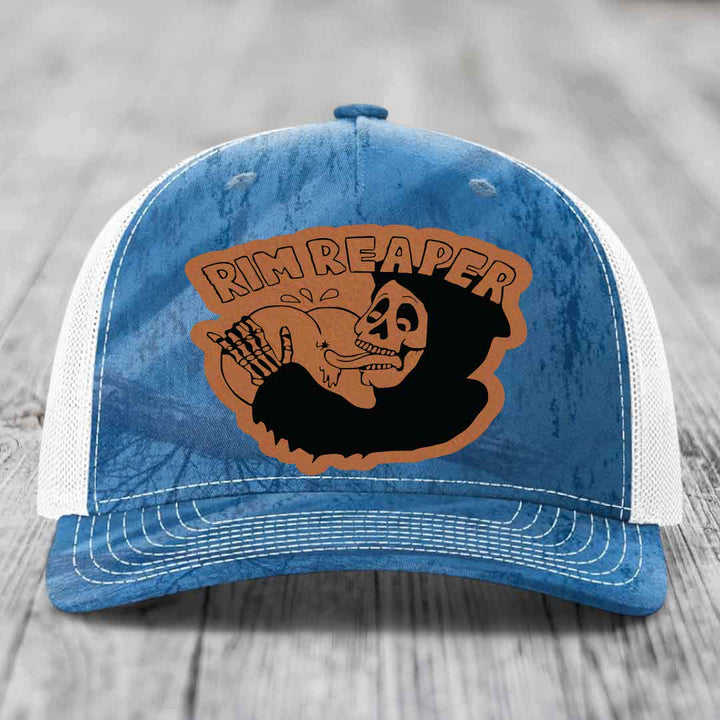 Blue and white trucker hat with a brown leatherette patch featuring a skeleton holding a basketball and the text &