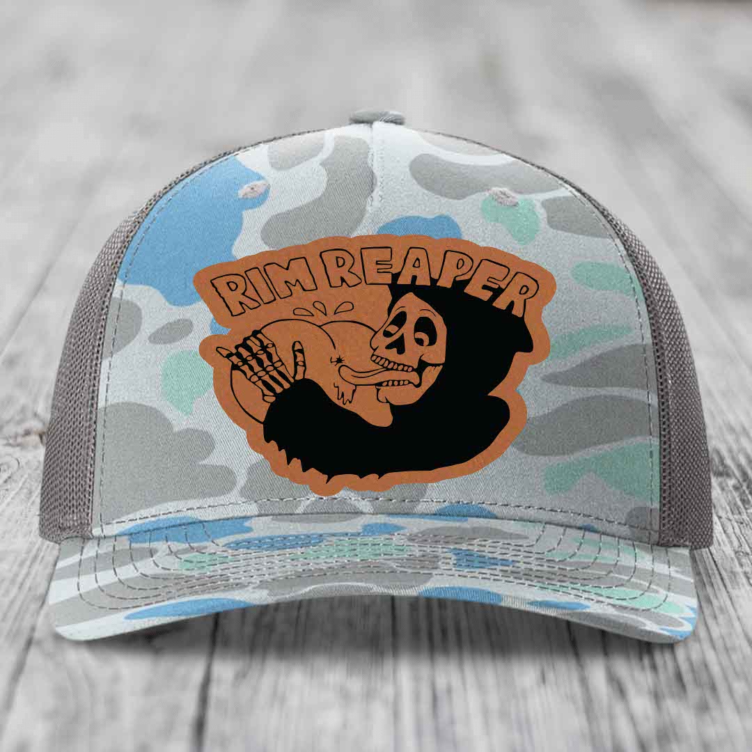 Camouflage trucker hat with brown leather patch featuring skull holding a golf club and &