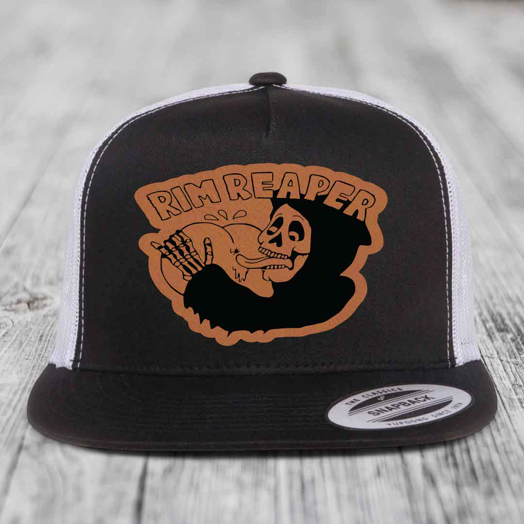 Black and white trucker hat with brown leather patch featuring a skeleton holding a golf club and text &