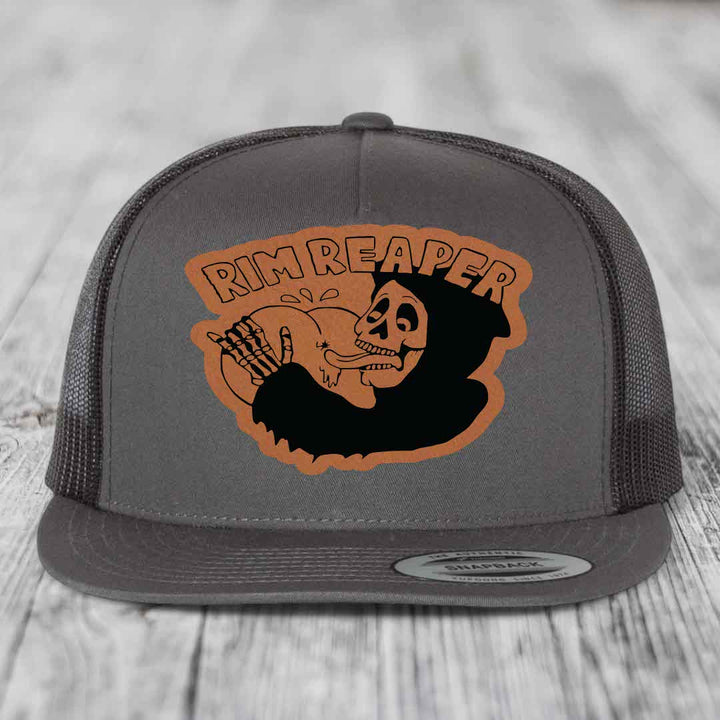 Grey trucker hat with brown leather patch featuring skull and &