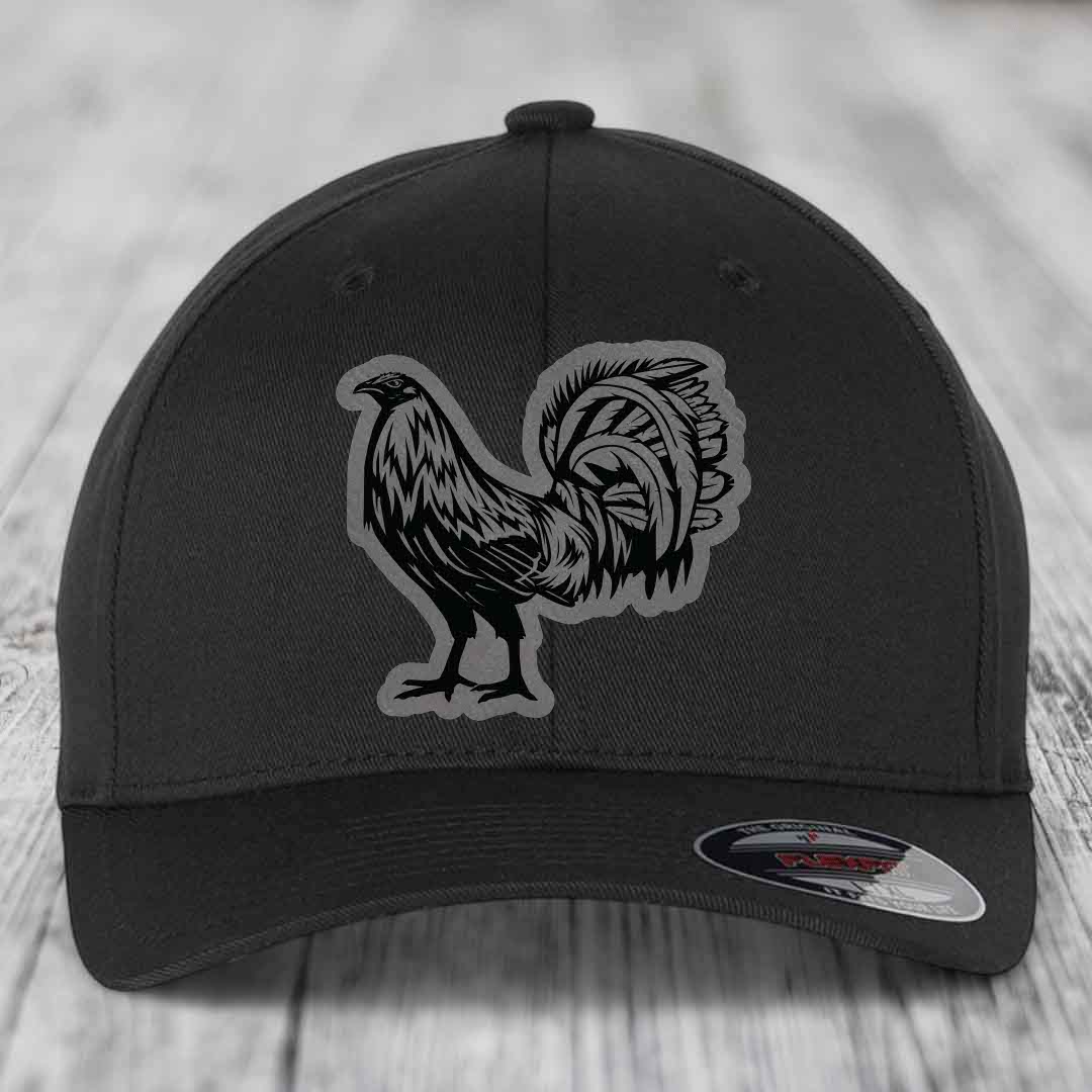 Black baseball cap with a rooster patch on front, sitting on wooden surface.