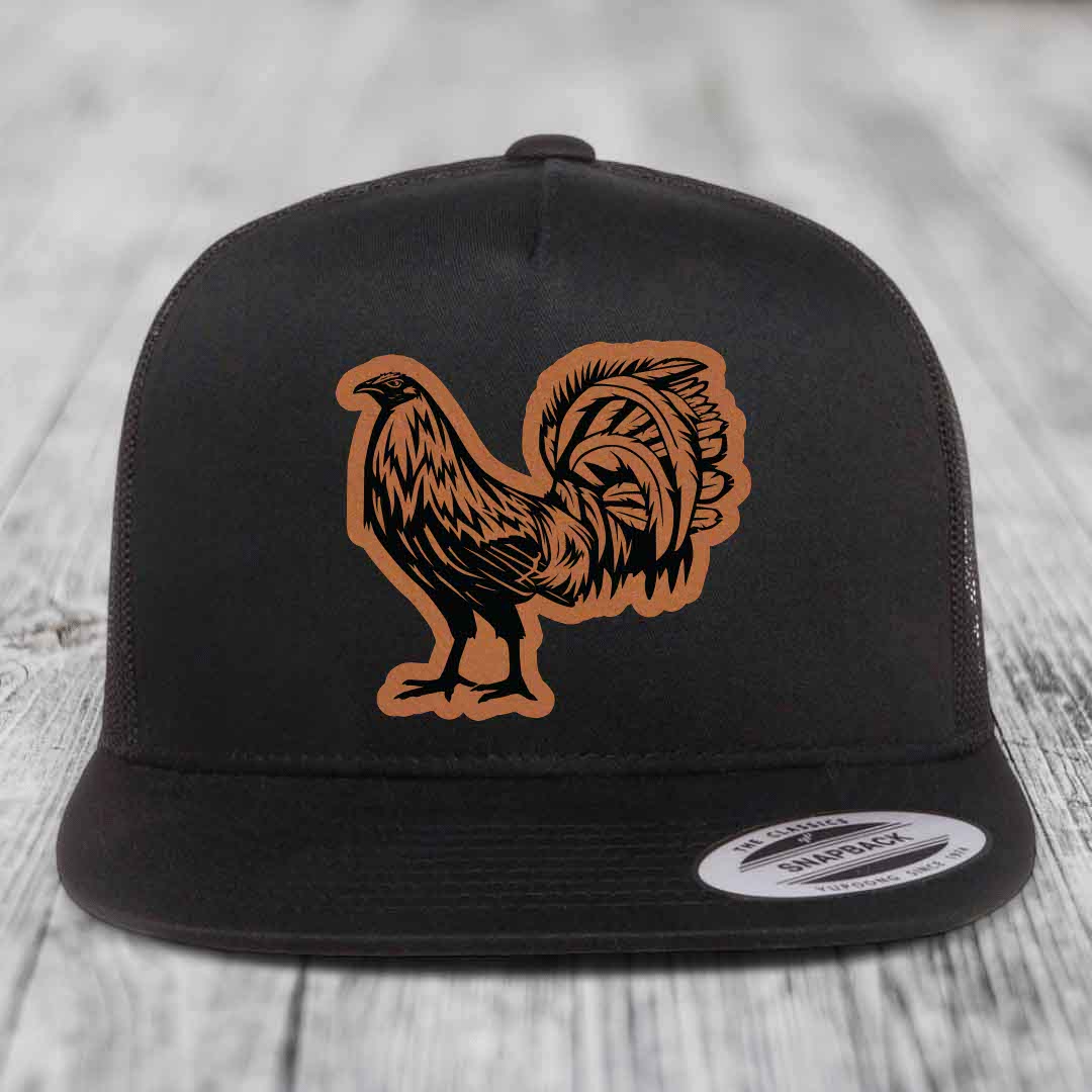 Black snapback hat with brown leather rooster patch on front, displayed on wooden surface.