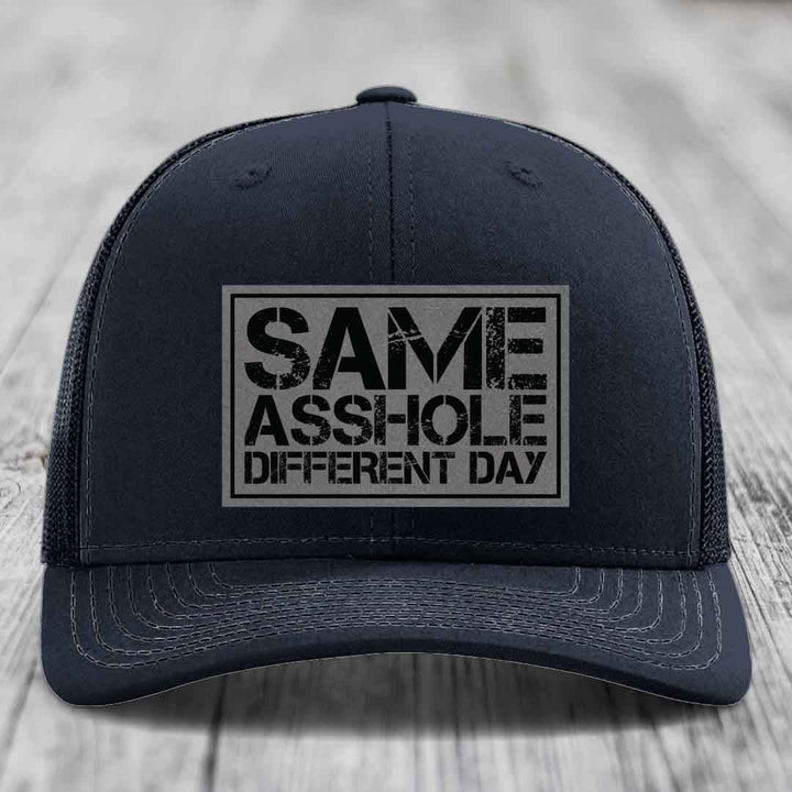 Black trucker hat with a rectangular patch that reads &