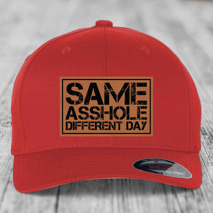 Red baseball cap with a brown leatherette patch reading &
