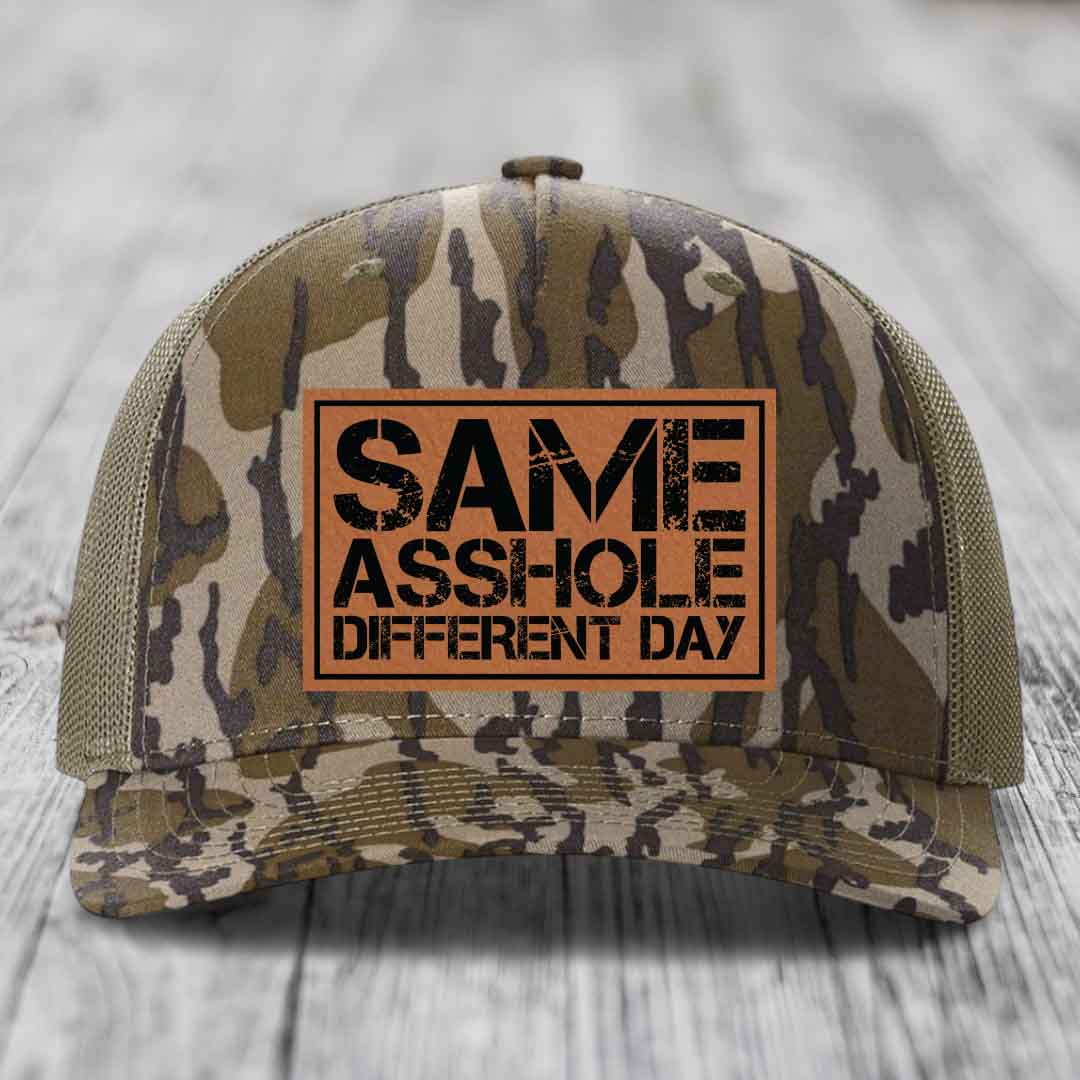 Camouflage trucker hat with brown leather patch reading &