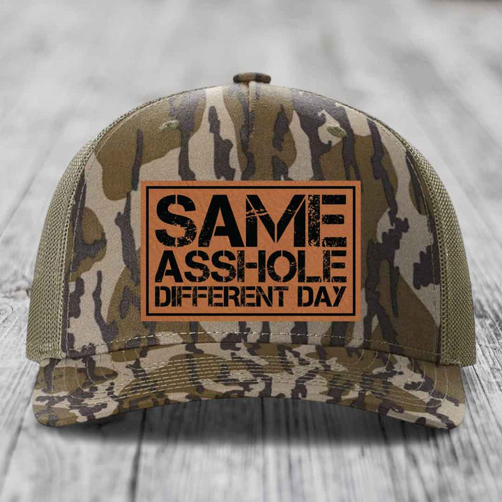 Camouflage trucker hat with brown leather patch reading &