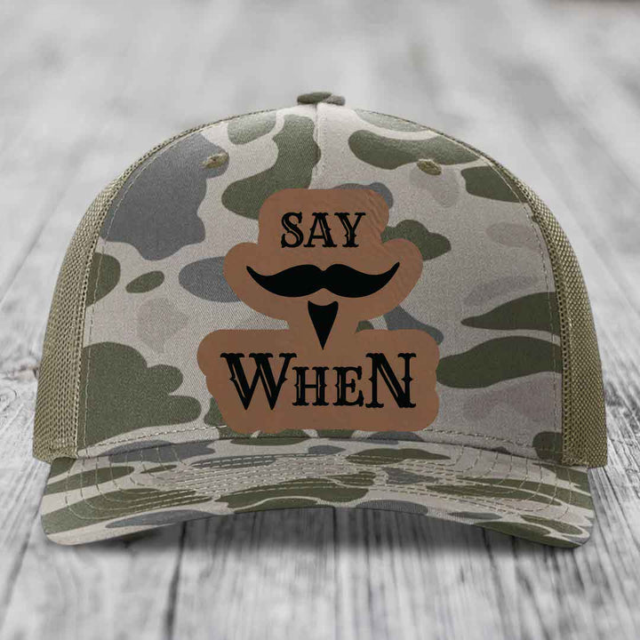Camouflage trucker hat with brown leather patch reading &