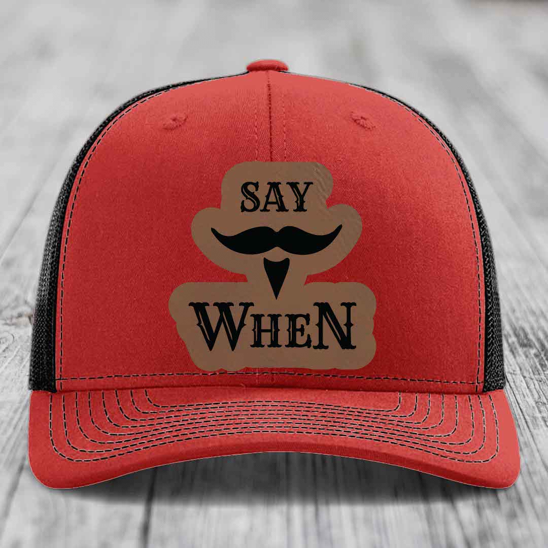 Red trucker hat with black mesh back and a brown leather patch that says &