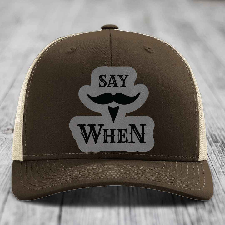 Brown trucker hat with cream mesh back and gray patch reading &
