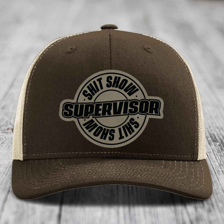 Brown trucker hat with beige mesh back and black embroidered &