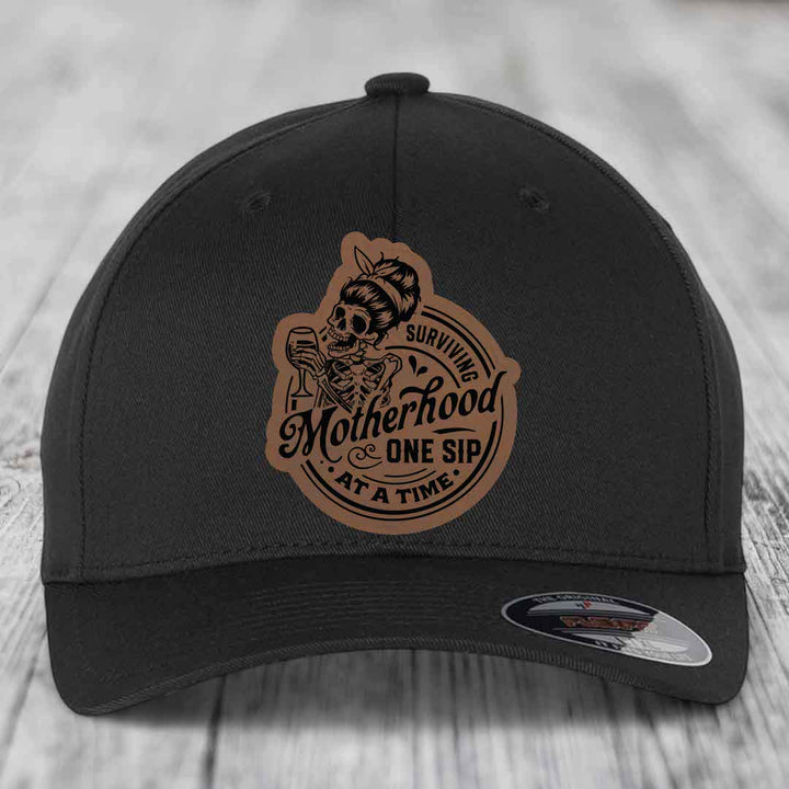 Surviving Motherhood, One Sip At A Time - Leather Patch Hat - Dark Brown to Black Patch - Flexfit 6277 Fitted Hat