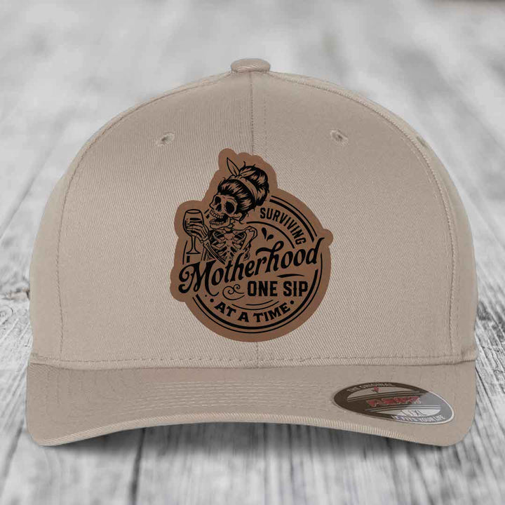 Surviving Motherhood, One Sip At A Time - Leather Patch Hat - Dark Brown to Black Patch - Flexfit 6277 Fitted Hat