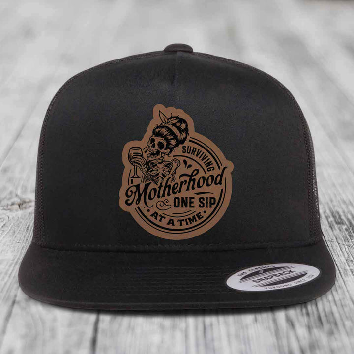 Surviving Motherhood, One Sip At A Time - Leather Patch Hat - Dark Brown to Black Patch - Yupoong 6006 Snapback Flatbill Hat
