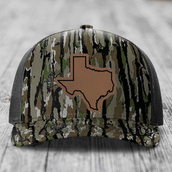 Camouflage trucker hat with brown Texas state outline patch on front.