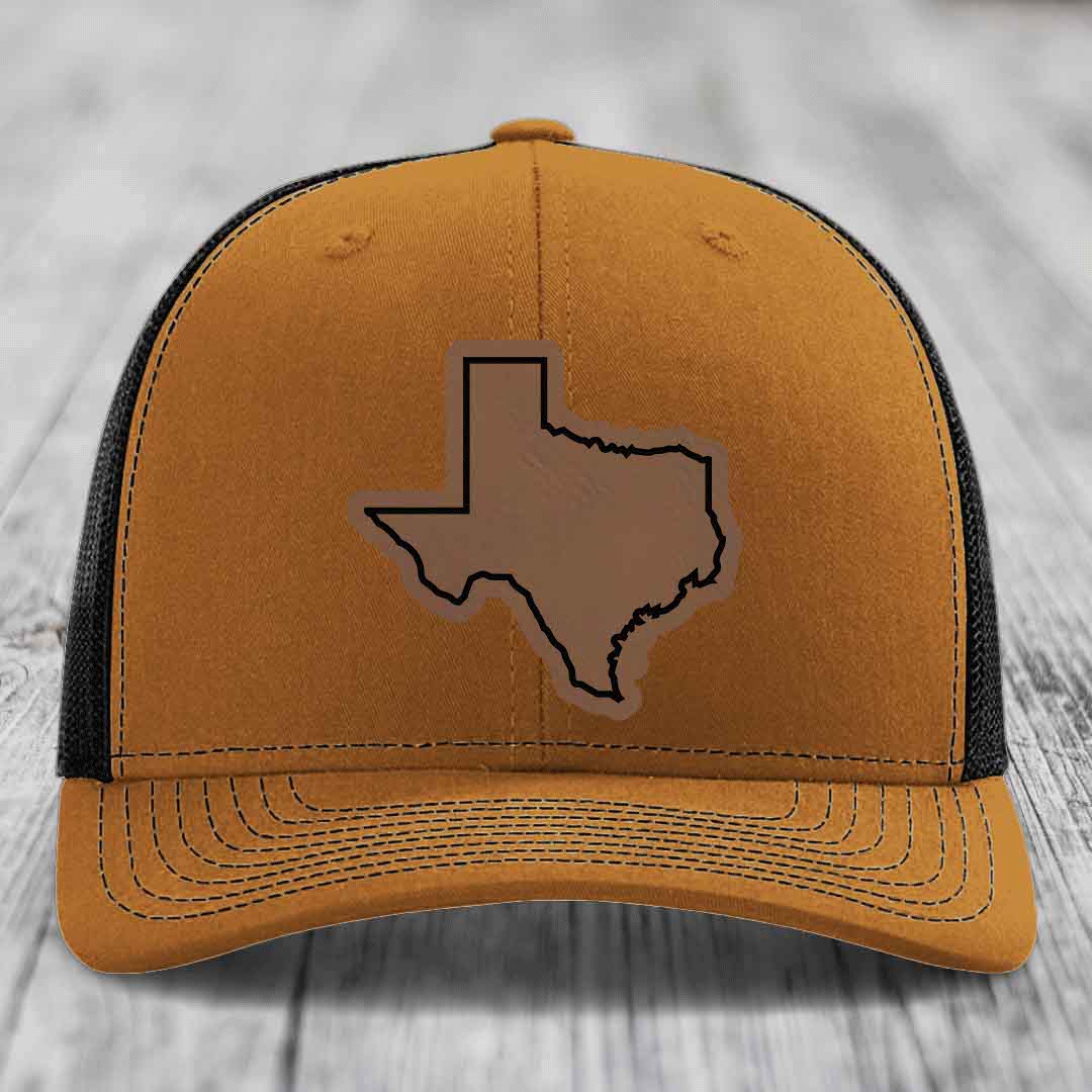 Tan trucker hat with black mesh back and Texas state outline leather patch on front.
