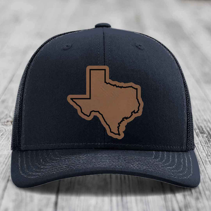 Black trucker hat with brown leather Texas state outline patch on front.