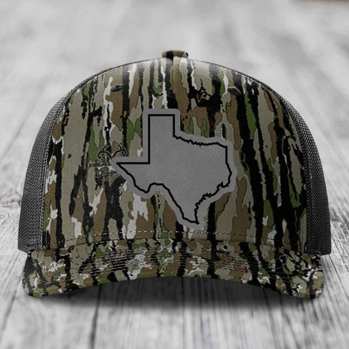 Camouflage trucker hat with gray Texas state outline patch on front.
