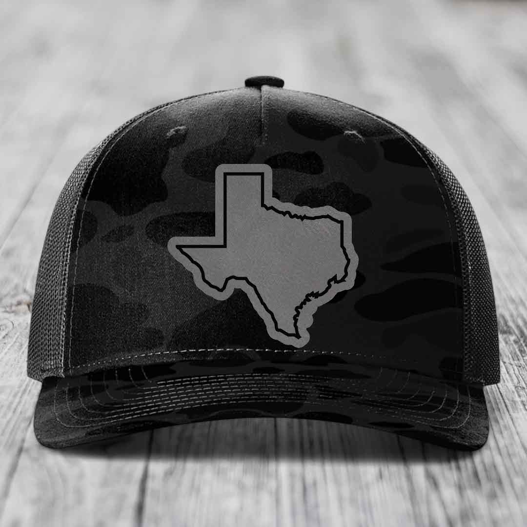 Black camouflage trucker hat with gray Texas state outline patch on front.