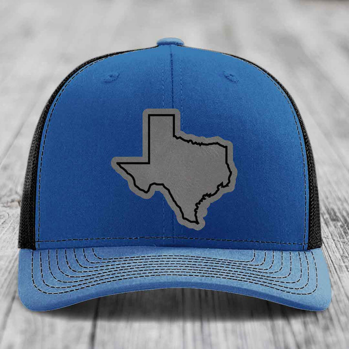 Blue trucker hat with gray Texas state outline patch on front, black mesh back.
