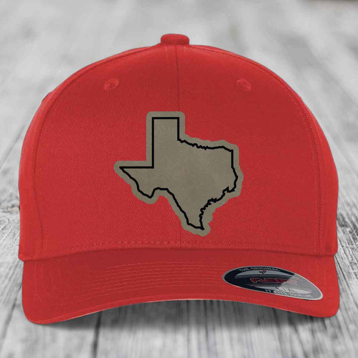 Red baseball cap with grey Texas state outline patch on front, Flexfit brand label visible.