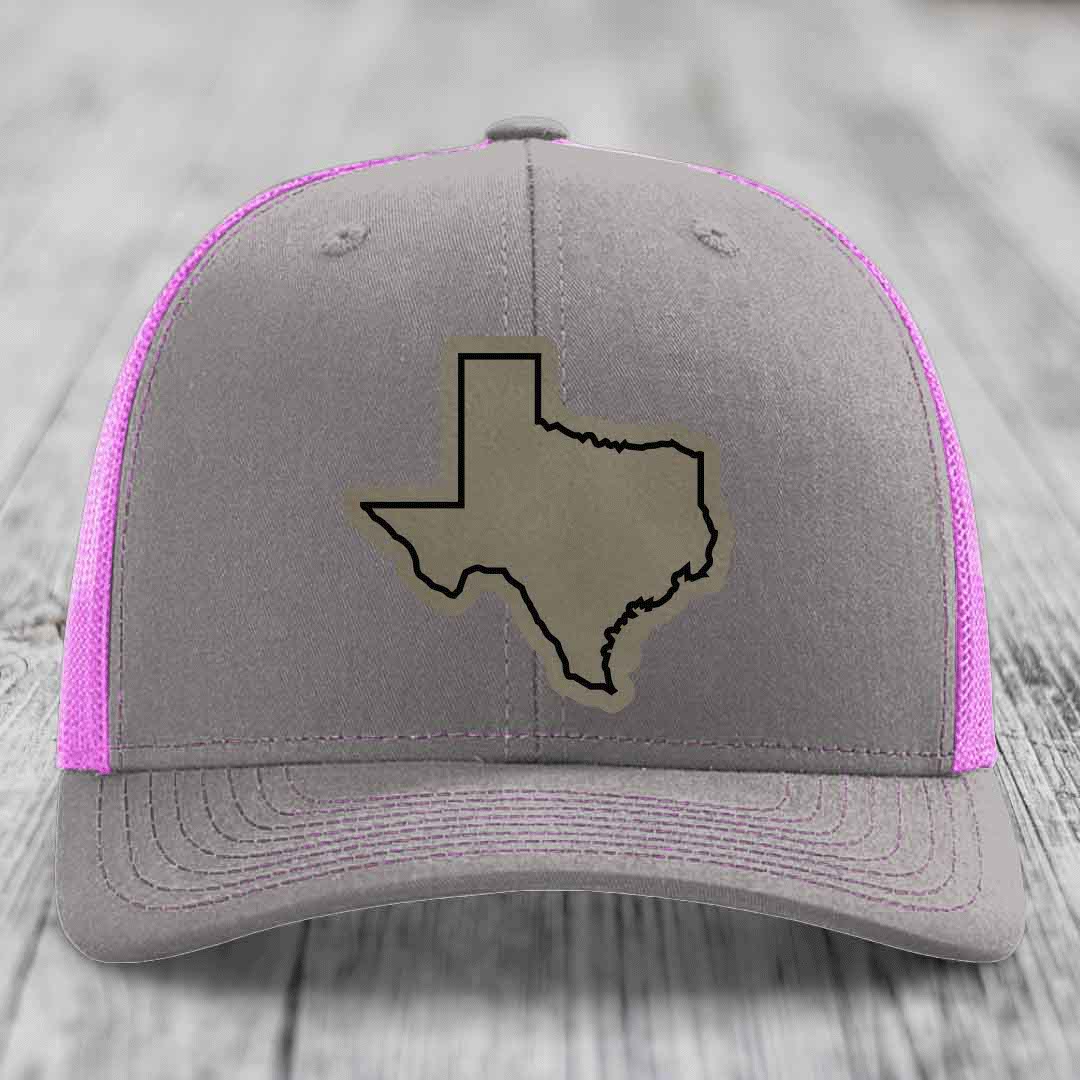 Grey trucker hat with pink mesh sides and a tan Texas state outline patch on front.