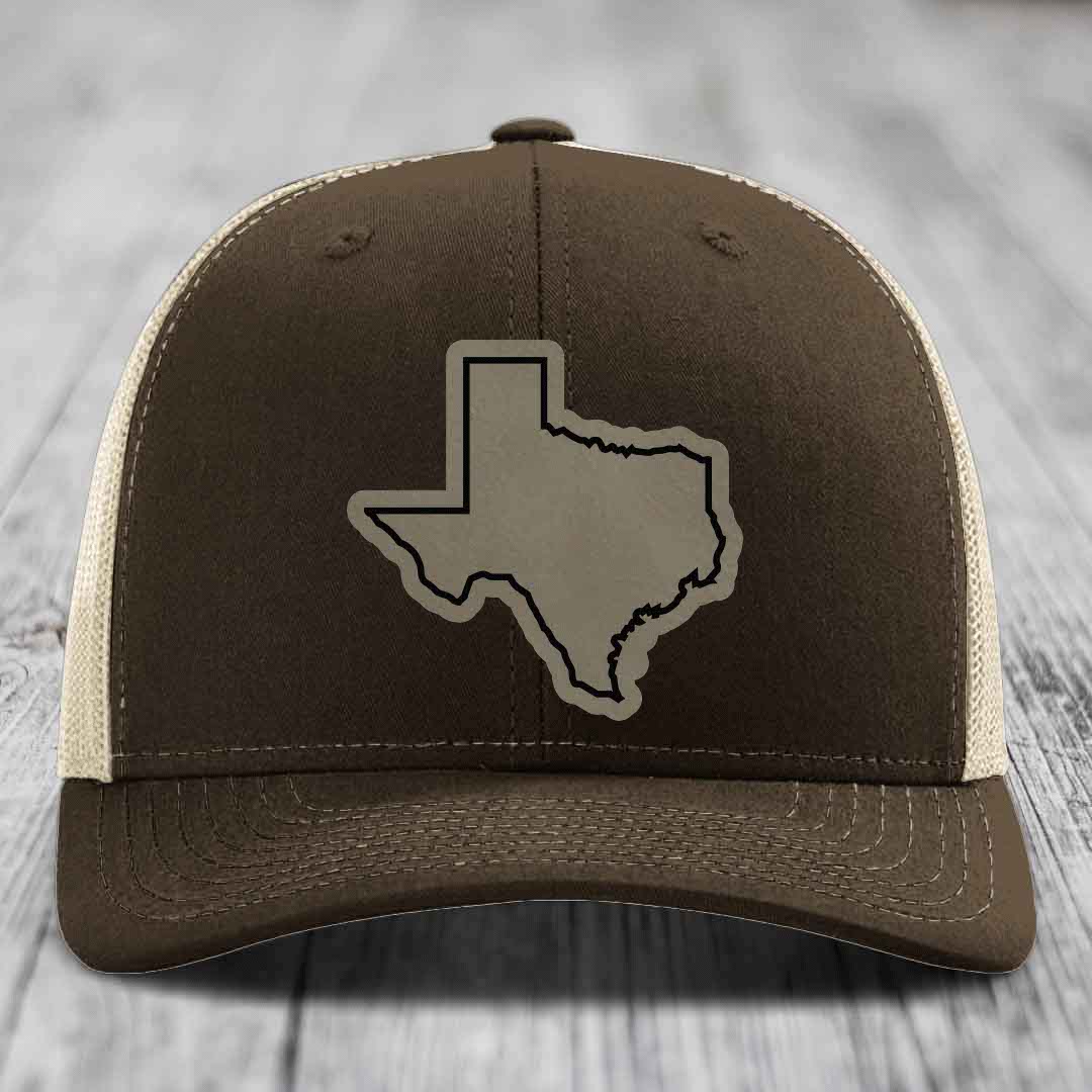 Brown trucker hat with Texas state outline patch on front, beige mesh back and stitching details.
