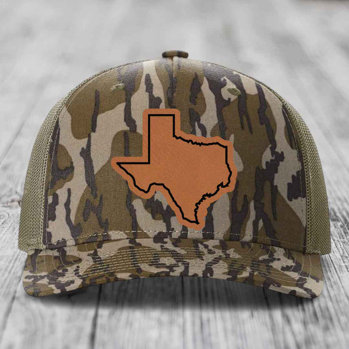 Camouflage trucker hat with brown Texas state outline patch on front.