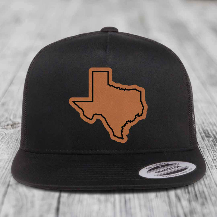 Black snapback hat with brown leather Texas state outline patch on front.