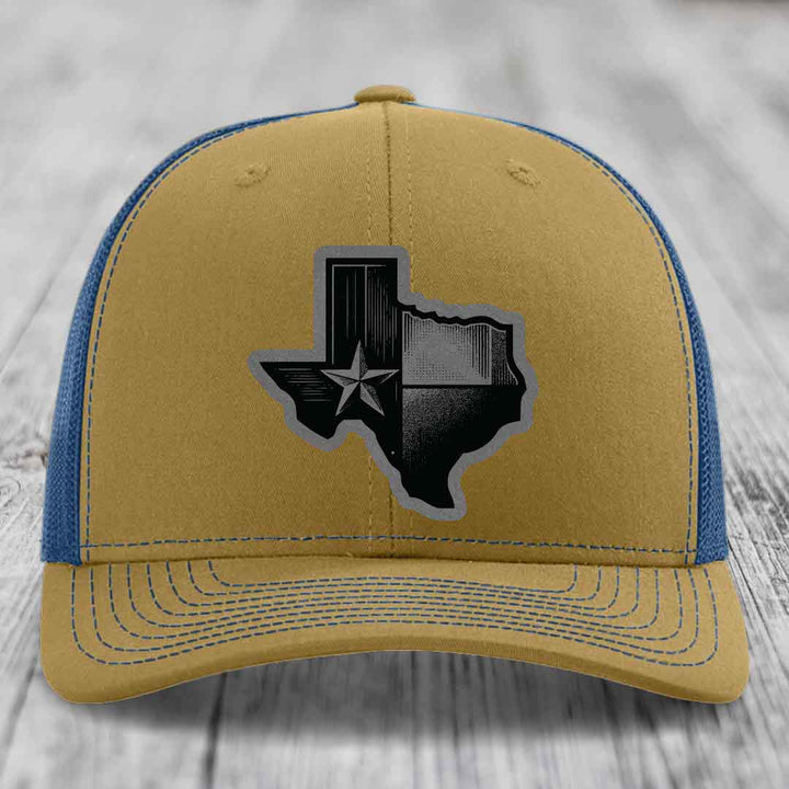 Tan and blue trucker hat with a black Texas-shaped leather patch featuring a star.